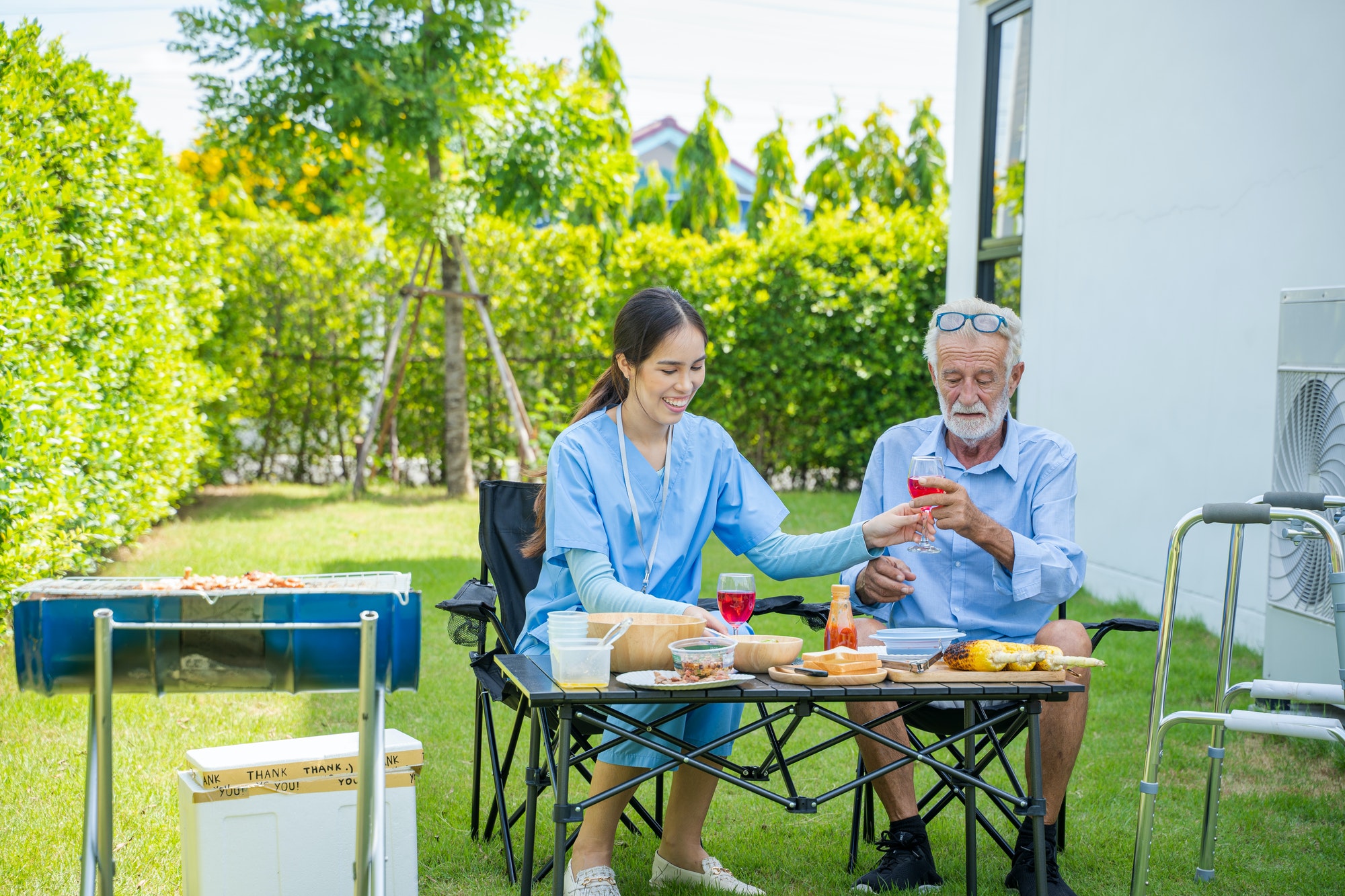 Elderly caregiver and man having a picnic in the garden on sunny day.